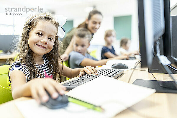 Lächelnder Schüler sitzt im Computerunterricht in der Schule