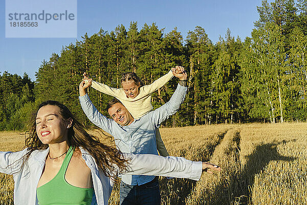Glückliche Familie  die an einem sonnigen Tag gemeinsam im Feld genießt