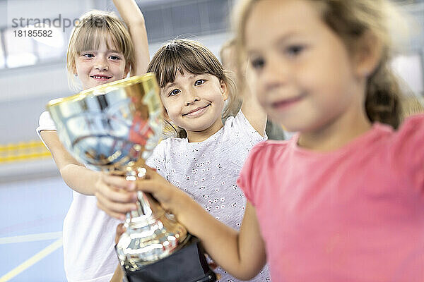 Schoolgirls celebrating victory with trophy at school sports court