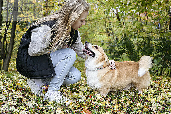 Blonde Frau streichelt Hund im Herbstwald