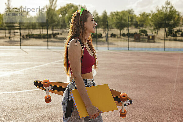 Frau läuft mit Akte und Skateboard im Sportplatz