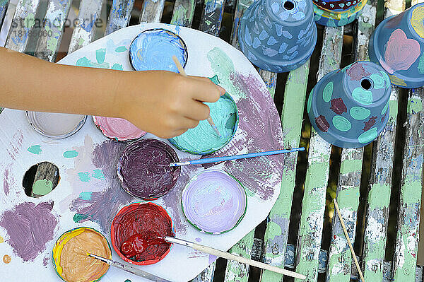 Hand of little girl painting flower pots