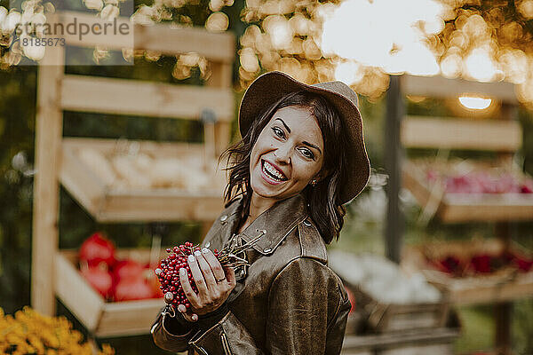 Lächelnde junge Frau hält Beerenfrüchte auf dem Markt