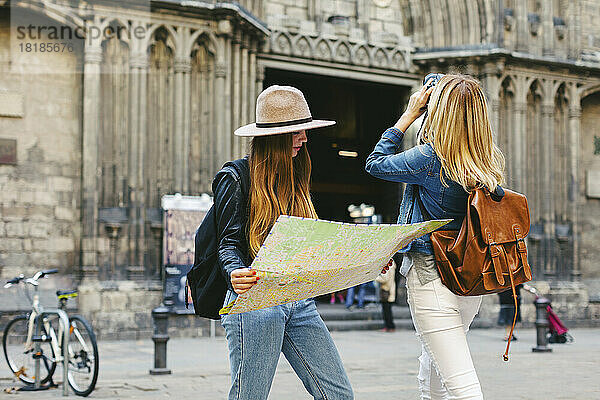 Spanien  Barcelona  ??zwei junge Frauen auf einem Platz mit Kamera und Karte