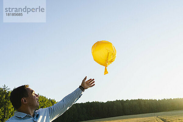 Glücklicher Mann greift auf dem Feld zum Müllsackballon
