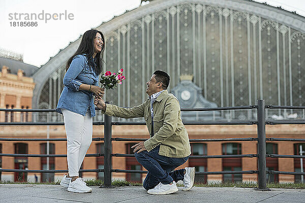 Glücklicher Mann schenkt Frau am Valentinstag Blumen und macht ihr auf dem Fußweg einen Heiratsantrag