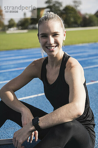 Smiling young sportswoman on running track