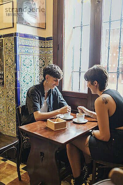 Glückliches junges Paar rührt Kaffee im Café