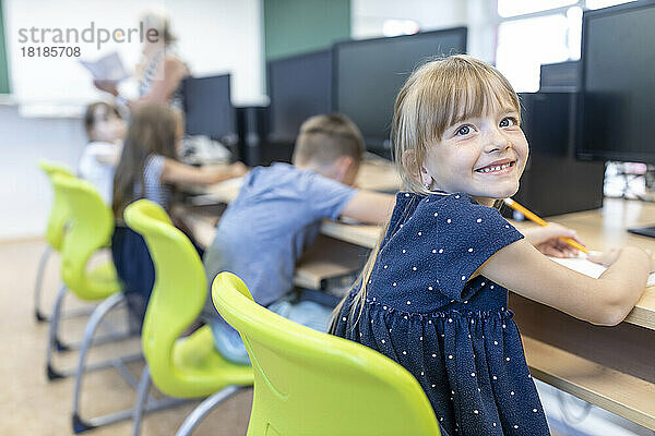 Smiling girl contemplating sitting at desk in classroom