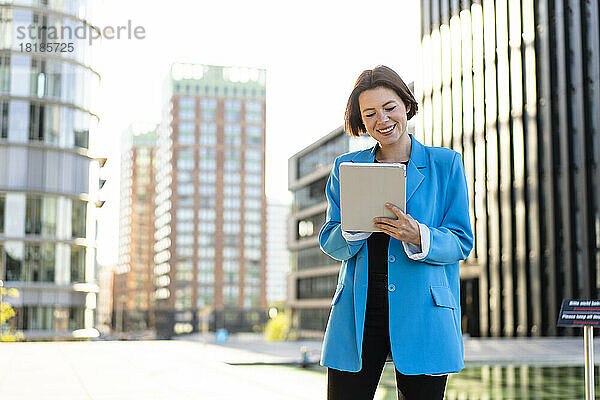Lächelnde Geschäftsfrau im blauen Blazer mit Tablet-PC