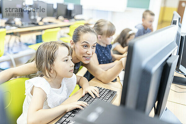 Schüler benutzen Computer mit Lehrer im Unterricht in der Schule