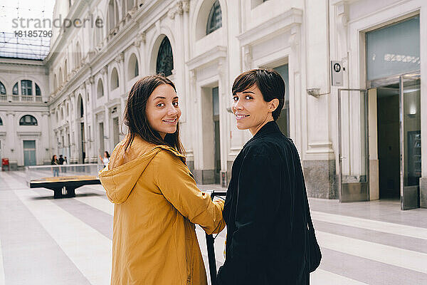 Lächelnde junge Frau mit Freundin im städtischen Gebäude