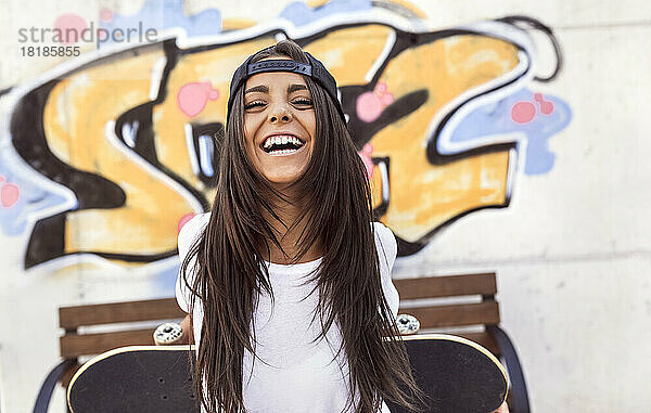 Laughing young woman holding skateboard