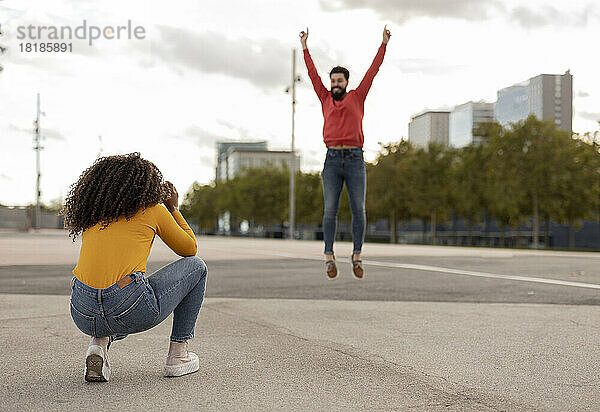 Frau fotografiert Freund  der auf Fußweg springt