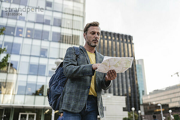 Mann mit Rucksack schaut auf die Karte in der Stadt