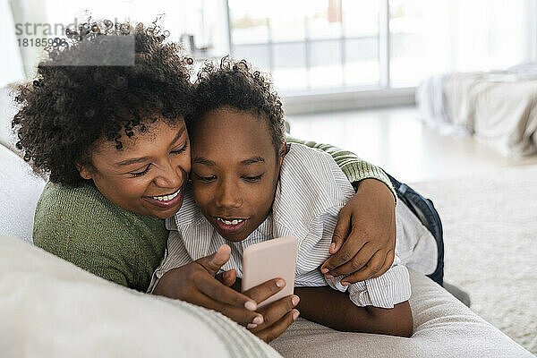 Glückliche Mutter mit Sohn  die zu Hause ihr Smartphone nutzt