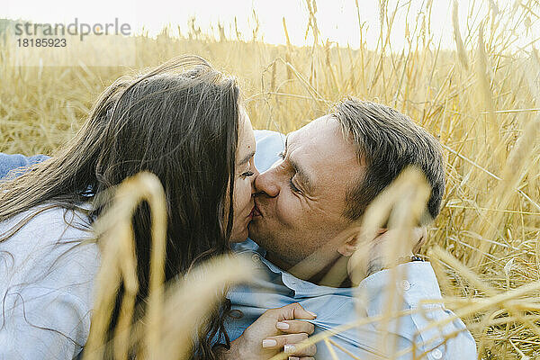 Romantic couple kissing amidst crops in field