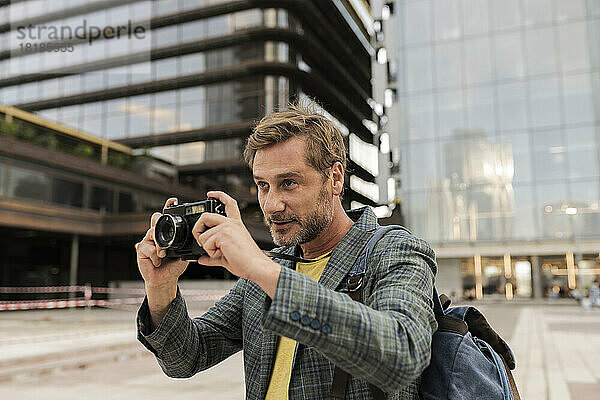 Mann fotografiert mit Kamera in der Stadt