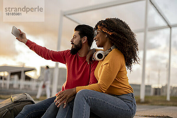Glückliche Frau und Mann machen bei Sonnenuntergang ein Selfie per Smartphone