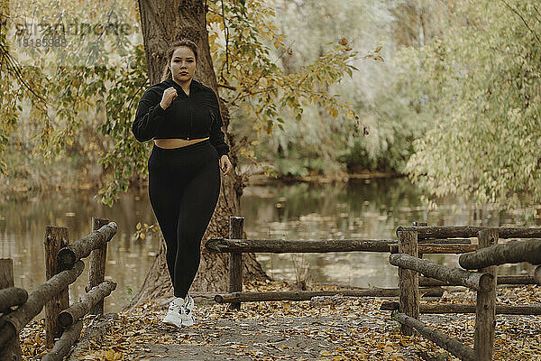 Entschlossene junge Frau joggt im Herbstpark