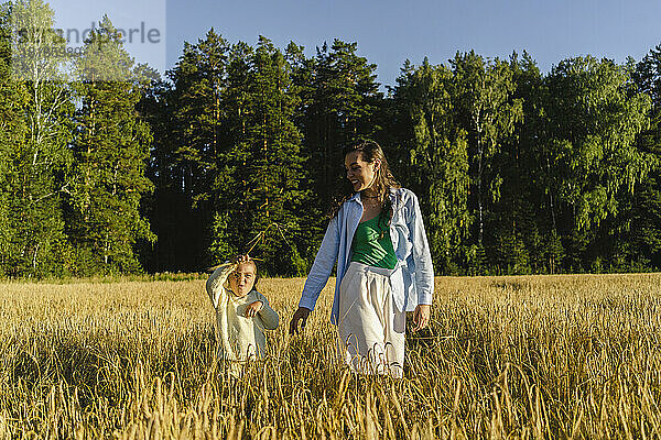 Glückliche Frau mit Tochter  die auf dem Feld läuft