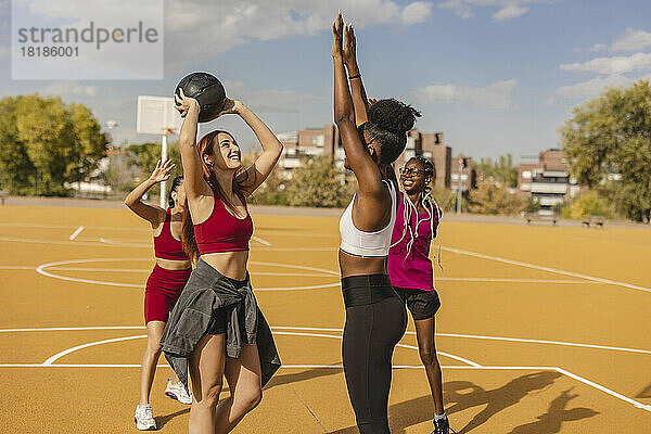 Freunde spielen Basketball auf dem Sportplatz