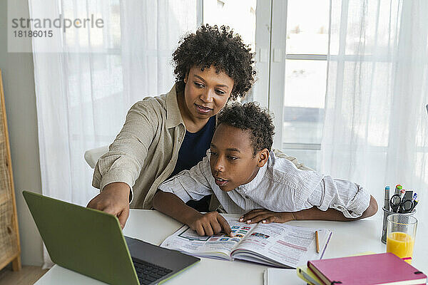 Mutter und Junge nutzen Laptop und lernen zu Hause
