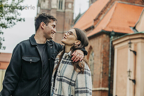 Lächelndes junges Paar  das einander in der Stadt anschaut