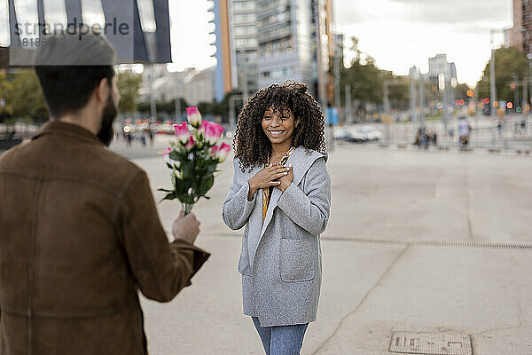 Junger Mann schenkt Frau am Fußweg einen Blumenstrauß