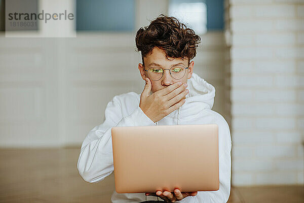 Überraschter Junge schaut auf Laptop