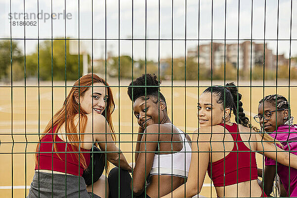 Glückliche junge Frauen sitzen zusammen am Sportplatz