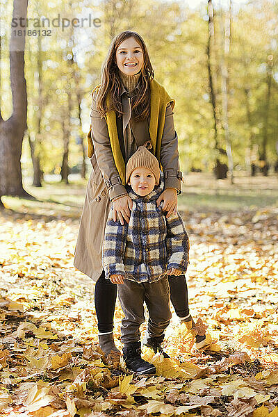 Glückliche Mutter und Sohn stehen auf Herbstblättern im Park
