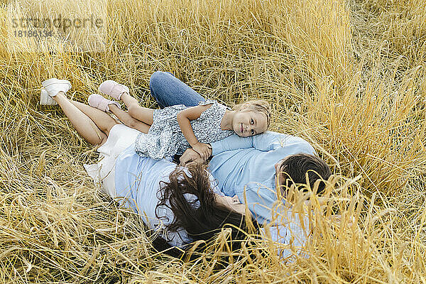 Lächelndes Mädchen entspannt sich mit Vater und Mutter inmitten von Feldfrüchten