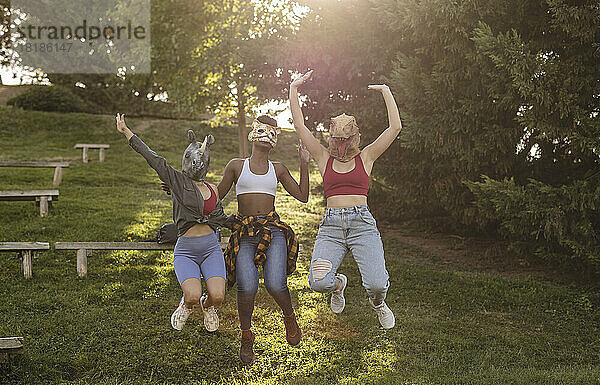 Frauen mit Tiermaske springen im Park