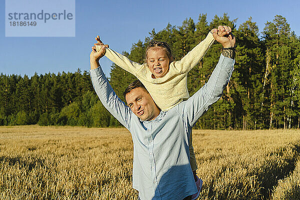Glücklicher Mann genießt es mit seiner verspielten Tochter im Feld