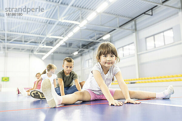 Mädchen übt Spagat mit Freunden am Schulsportplatz