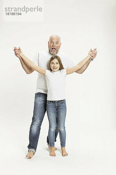 Vater spielt mit Tochter vor weißem Hintergrund im Studio