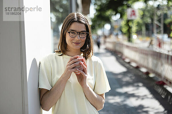 Lächelnde Geschäftsfrau hält Kaffeetasse auf Fußweg