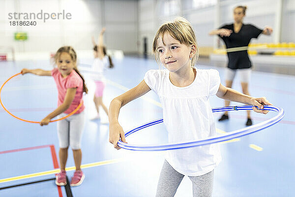 Mädchen übt Hula-Hoop auf dem Schulsportplatz