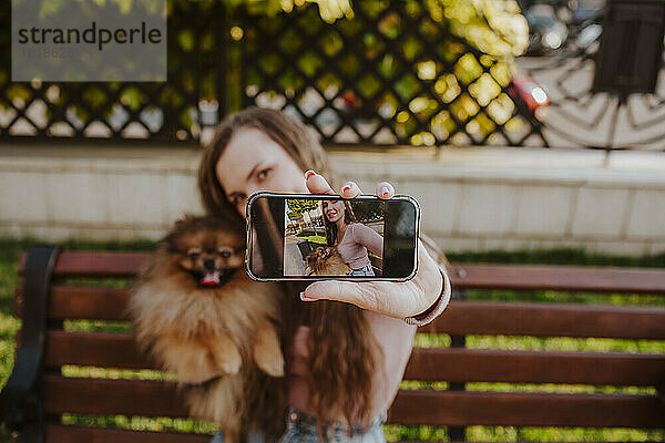 Frau zeigt ihr Selfie mit Hund auf dem Handy