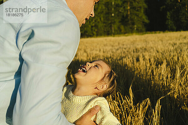 Glückliches Mädchen  das an einem sonnigen Tag mit seiner Tochter auf dem Feld spielt