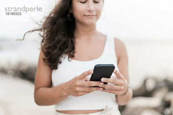 Junge Frau benutzt Smartphone am Strand