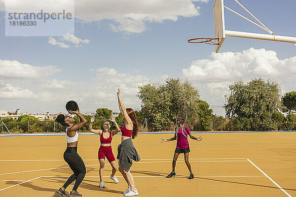 Freunde haben Spaß beim Basketballspielen auf dem Sportplatz