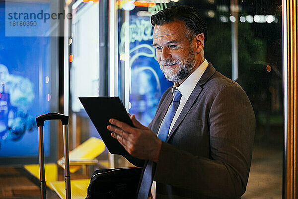 Reifer Geschäftsmann nutzt nachts Tablet-PC