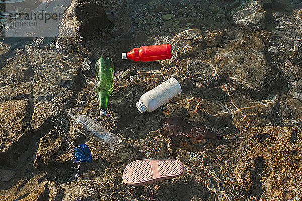 Leere Plastikflaschen und Hausschuhe schwimmen auf dem Wasser