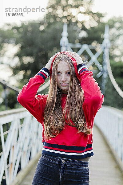 Porträt eines Teenager-Mädchens auf einer Brücke  roter Kapuzenpullover