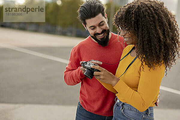 Glücklicher junger Mann mit Freundin hält Kamera am Fußweg
