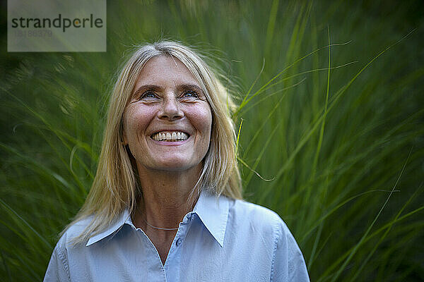 Happy mature woman standing in front of plant