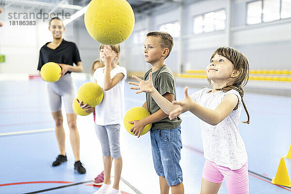 Grundschüler spielen mit Ball auf dem Schulsportplatz