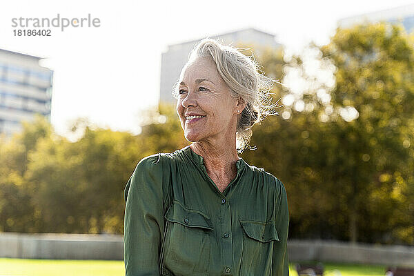 Lächelnde reife Frau mit grauen Haaren im Park